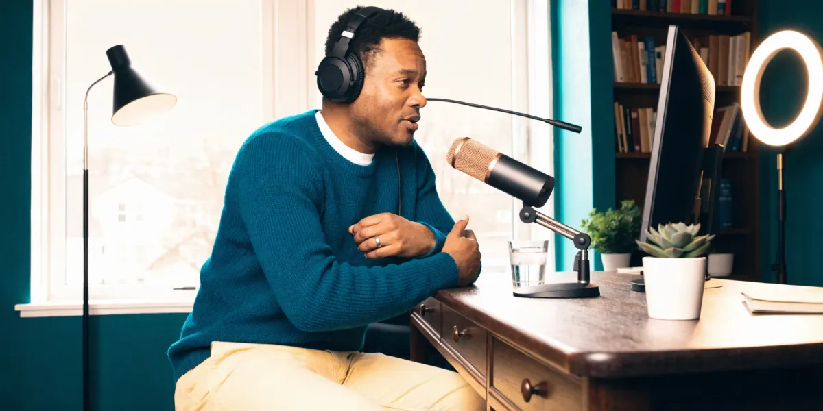 Professional podcaster speaking into a microphone at a home office desk