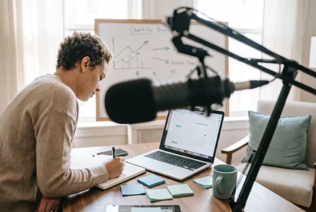 Podcast host mapping out a business-focused content strategy at a home studio desk